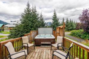 a deck with a hot tub and chairs on it at Alpina Cabin in Girdwood