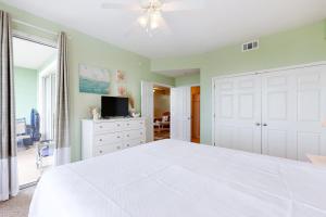 een slaapkamer met een wit bed en een televisie bij Navy Cove Harbor 1306 in Gulf Shores