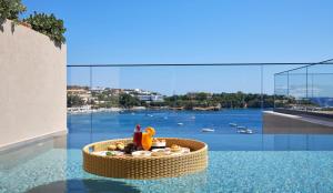 einen Pool mit einem Tisch mit Essen und Blick auf das Wasser in der Unterkunft Castello Infinity Suites - Adults Only in Agia Pelagia