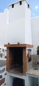 einen Außenkamin mit einer weißen Wand und einem Ziegelstein in der Unterkunft Casa marroquina in Las Indias