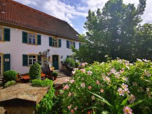 a white house with green shutters and flowers at Landgasthof Büttel in Geisfeld