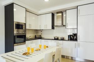 a kitchen with white cabinets and a white table and chairs at Clerigo - Holiday Apartments - By SCH in São Martinho do Porto