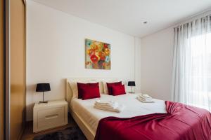 um quarto com uma cama branca e almofadas vermelhas em Clerigo - Holiday Apartments - By SCH em São Martinho do Porto