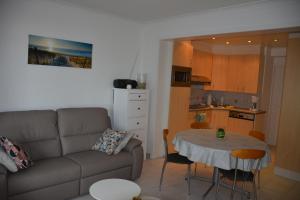 a living room with a couch and a table and a kitchen at Zijdezeezicht Martiny 0202 in Middelkerke