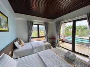 a bedroom with two beds and a balcony at Tam Coc Elegance House in Ninh Binh