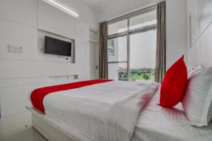 a bedroom with a large bed with red pillows and a window at Grande Azure in Jaipur