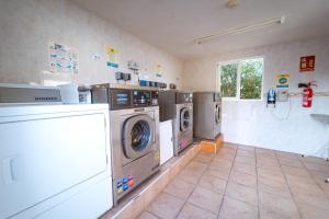 a laundry room with three washing machines and a shower at Kampaoh Playa de Levante in Benidorm