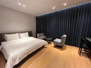 a bedroom with a bed and a table and chairs at Jinhae Intercity Hotel in Changwon