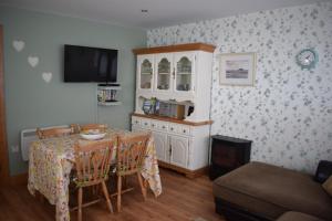 een eetkamer met een tafel met stoelen en een tv bij Cosy two bedroom cottage on the Mullet Peninsula in Ballina