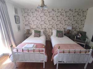two beds in a bedroom with floral wallpaper at Les Houstalous in Lacombe
