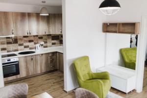 a kitchen with wooden cabinets and a green chair at Class Apartment in Brčko