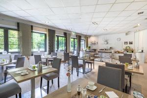 ein Restaurant mit Tischen, Stühlen und Fenstern in der Unterkunft Hotel Freiraum in Mönchengladbach