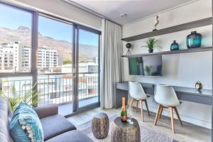 ein Wohnzimmer mit einem Sofa und Stühlen sowie einem großen Fenster in der Unterkunft Contemporary arty Studio Balcony Mountain views in Kapstadt