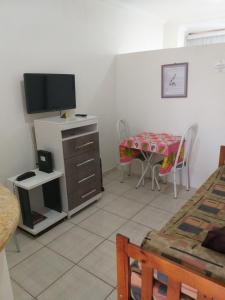 Zimmer mit einem Tisch und einem TV sowie einem Tisch und Stühlen in der Unterkunft Flat em Pitangueiras - Guarujá in Guarujá