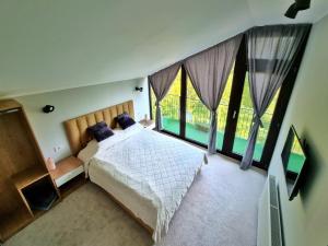 Casa Yla في بياترا نيامت: غرفة نوم بسرير ونوافذ كبيرة