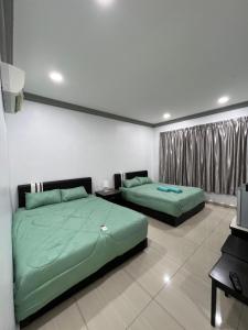 two green beds in a room with a television at Ourstay Nadi Kota in Bandar  Pusat Jengka