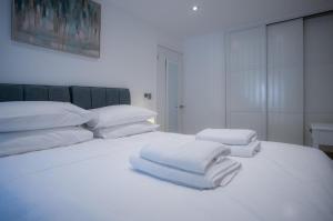 a white bed with white sheets and pillows on it at Beach Court - 1 Bedroom Apartment - Saundersfoot in Saundersfoot