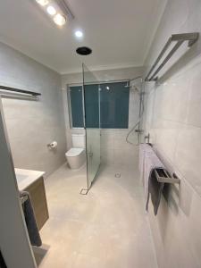 La salle de bains est pourvue d'une douche en verre et de toilettes. dans l'établissement Waterside Canal Dreams, à Mandurah