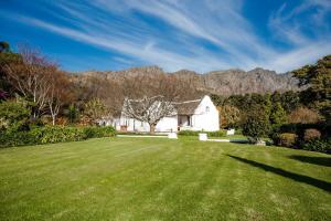 a large yard with a white house with mountains in the background at Cape Dutch @ Keerweder in Franschhoek