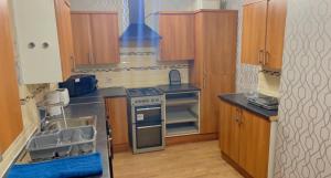 a kitchen with wooden cabinets and a stove top oven at Manchester Old Trafford Apartment in Manchester