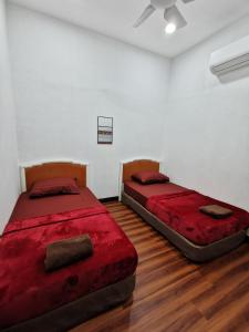 - 2 lits dans une chambre dotée de parquet dans l'établissement SinggahSini Homestay Melaka, 