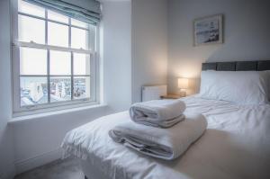 Un dormitorio blanco con una cama con toallas. en Upper Deck - 2 Bedroom Apartment - Saundersfoot, en Saundersfoot