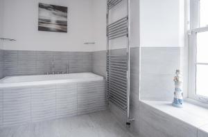 y baño blanco con bañera y ducha. en Upper Deck - 2 Bedroom Apartment - Saundersfoot, en Saundersfoot