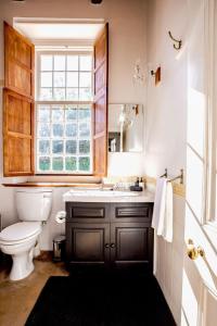 a bathroom with a toilet and a sink and a window at Cape Dutch @ Keerweder in Franschhoek