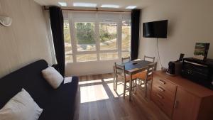 a living room with a couch and a table and a window at Le Portillo in Puy-Saint-Vincent