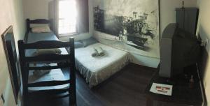 Habitación pequeña con cama y TV. en Nuh Hostel en Ouro Preto