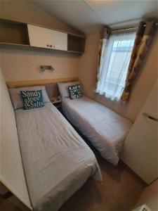 Habitación pequeña con 2 camas y ventana en K17 Lake View en Paignton