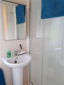 ein Bad mit einem Waschbecken und einer Dusche mit einem Spiegel in der Unterkunft K17 Lake View in Paignton
