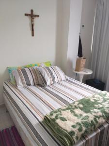ein Bett in einem Zimmer mit einem Kreuz an der Wand in der Unterkunft Flat em Pitangueiras - Guarujá in Guarujá