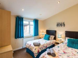 a bedroom with two beds and blue curtains at Windermere Retreat - White Cross Bay Holiday Park in Windermere