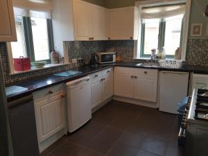 a kitchen with white cabinets and black counter tops at Ideally located Cumbrian home with stunning views in Seascale