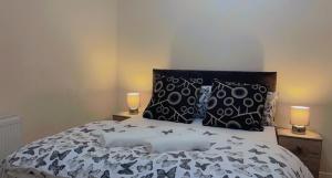 a bedroom with a bed with black and white sheets and two candles at Manchester Old Trafford Apartment in Manchester