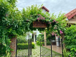 einen Zugang zu einem Garten mit einem Tor mit Blumen in der Unterkunft Tam Coc Elegance House in Ninh Bình
