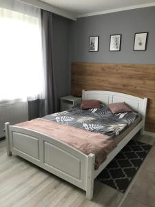 a bedroom with a white bed with a wooden headboard at Rybacka 48 - Twoje miejsce wypoczynku, domki, pokoje, apartamenty in Jantar