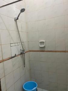 a shower in a tiled bathroom with a blue bucket at Lippo Carita Ocean View Lantai Dasar by Hello Beach in Carita