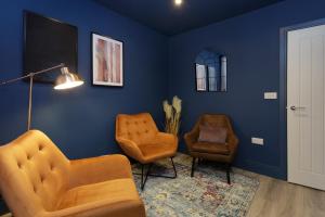 a living room with blue walls and two chairs at Beatrice Manor - Luxury 4 bedroom house in central Southsea, Portsmouth in Portsmouth