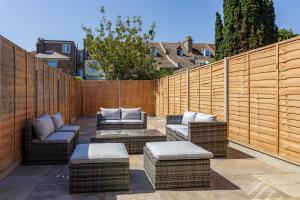 a patio with wicker furniture and a wooden fence at Beatrice Manor - Luxury 4 bedroom house in central Southsea, Portsmouth in Portsmouth