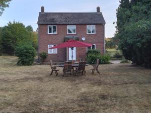 a table with chairs and an umbrella in front of a house at Avryn - Delightful 3 bedroom cottage with stunning vistas in Mainstone