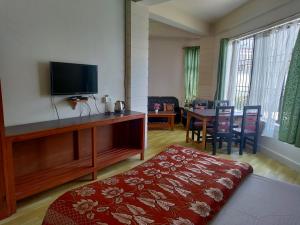 a living room with a television and a table with chairs at The Shillong Hills Guest House in Shillong