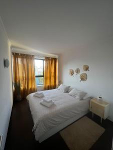 a white bedroom with a large bed and a window at Portas d'Água - Apartamento entre o Mar e a Ria in Gafanha da Nazaré