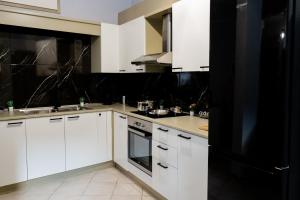 a kitchen with white cabinets and a black refrigerator at Μοντέρνο Σπίτι στην καρδιά του κάστρου Ιωαννίνων in Ioannina +3 photos