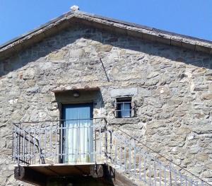 um edifício de pedra com uma varanda e uma janela em Two-room apartment in Tuscan rustic style em La Lama