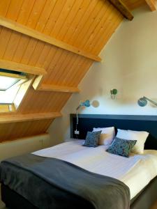 een bed in een kamer met houten plafonds bij Aan de Molenberg in Broekhuizen