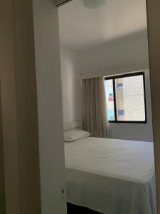 1 dormitorio con 1 cama blanca y ventana en Vila Costeira Flat Apto Particular, en Fortaleza
