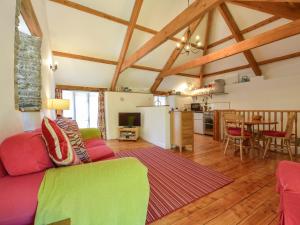 ein Wohnzimmer mit einem roten Sofa und einer Küche in der Unterkunft Parsonage Farm Cottage in Newton Ferrers