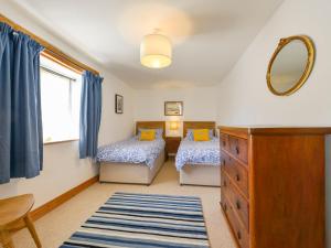 a bedroom with two beds and a mirror and a dresser at Parsonage Farm Cottage in Newton Ferrers